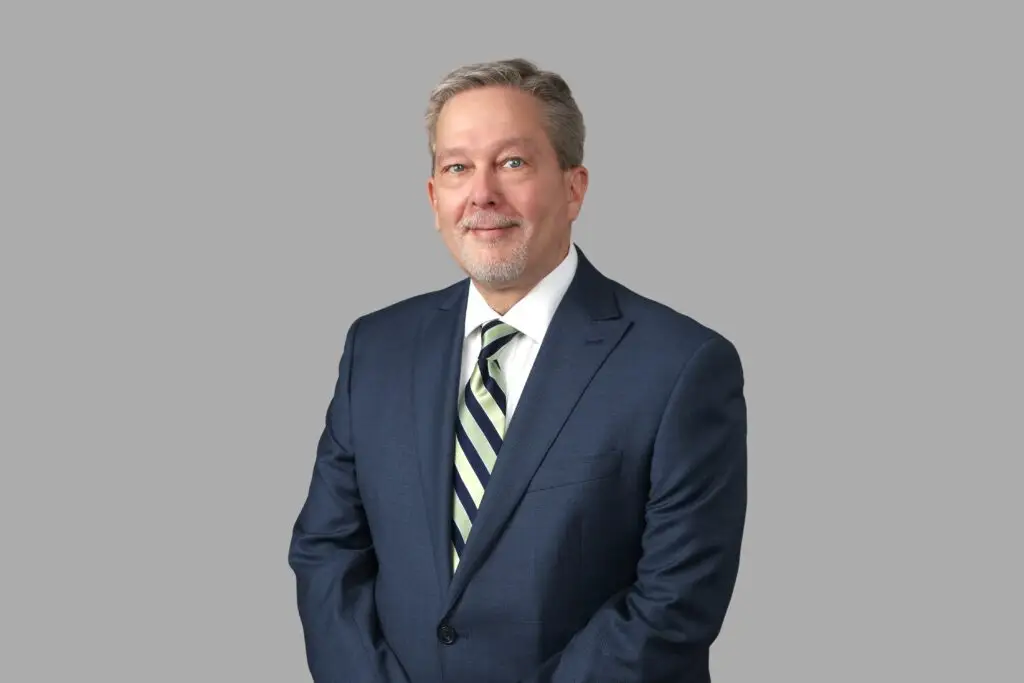 Portrait of an elderly man in a suit with a striped tie.