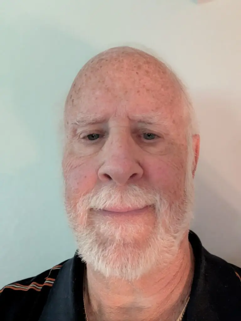Close-up of a smiling elderly man with a white beard and mustache.